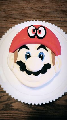 a white plate topped with a cake covered in icing and a mario bros hat