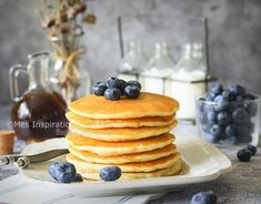 a stack of pancakes topped with blueberries and syrup