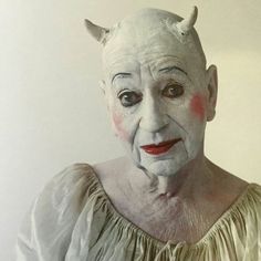 an old woman with white makeup and devil horns on her head