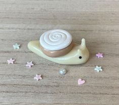 a small toy snail sitting on top of a wooden table next to tiny pink and white stars