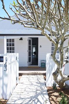 a white house with a tree in front of it and the door to the room is open