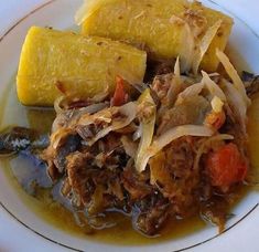 a white plate topped with meat and veggies covered in gravy next to corn on the cob