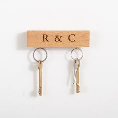 two keys hang on a key holder with the word r & c engraved on it