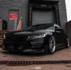 a black car is parked in front of a building with stairs and a garage door