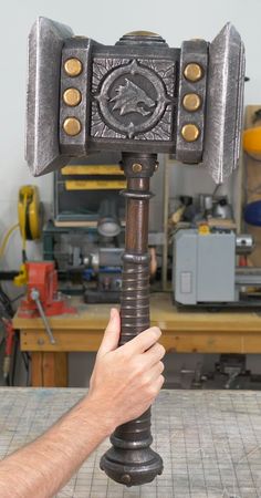 a man holding an old metal hammer in his hand