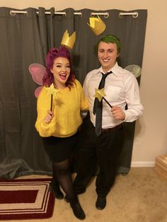 two people dressed in costumes standing next to each other, one holding a wand and the other smiling