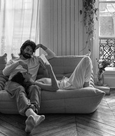 a man sitting on top of a couch next to a woman laying on the floor