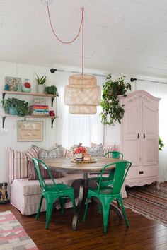 a dining room table with green chairs and pink cabinets