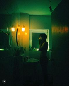 a woman standing in front of a bathroom mirror holding a cell phone to her ear