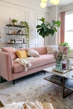 a living room with pink couches and potted plants on the table in it