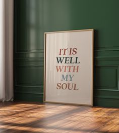 there is a framed poster on the floor in front of a green wall that says it is well with my soul