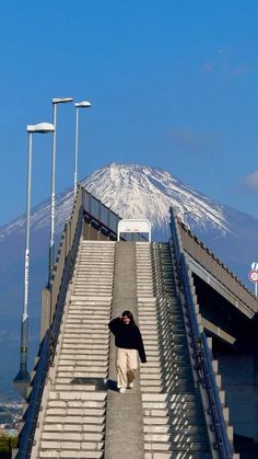 a man walking up some stairs with a snow covered mountain in the backgroud