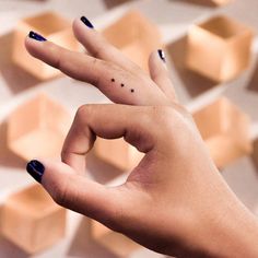 a woman's hand with two fingers and stars on the middle finger, in front of hexagonal tiles