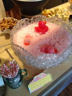 a cake with pink frosting and rubber ducks on top, surrounded by candy sticks