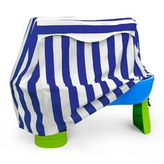 a blue and white striped cover on a green plastic table with a stool underneath it