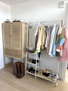 an organized closet with clothes and shoes hanging on the rack, next to a cabinet