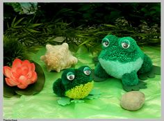 three stuffed animals sitting next to each other on a green cloth covered ground with leaves and flowers