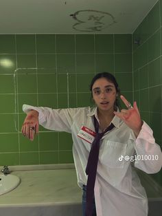 a woman standing in front of a bathroom sink wearing a white shirt and purple tie