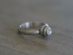 This unique sterling silver and spinel statement ring was handmade by me in my studio- Two stacked sterling silver pebbles, reminiscent of a cairn, hold a delicate, rose cut spinel cabochon, set in fine silver. The stone has a translucent pale lavender hue and adds a beautiful contrast to the rugged structure of the metal work. The surface of the sterling silver was textured and oxidized. This is a statement ring with an earthy, organic feel. Measurements: Size: US 8 Stone: rose cut spinel 4.7x4 Hand Forged Silver Diamond Ring, Fine Silver Hand Forged Rings, Unique Silver Stackable Rings With Bezel Setting, Unique Silver Sapphire Promise Ring, Unique Handmade Diamond Promise Ring, Hand Forged Sterling Silver Crystal Ring, Hand Forged Sterling Silver Sapphire Ring For Anniversary, Unique Handmade Sterling Silver Topaz Ring, Hand Forged Sterling Silver Crystal Promise Ring