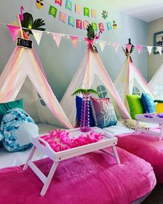 a bedroom decorated in pink and white with teepees