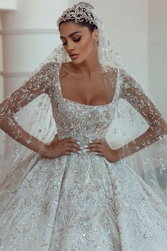 a woman wearing a wedding dress with long sleeves and a veil on her head is posing for the camera