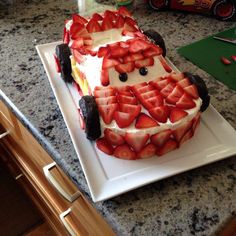 a cake shaped like a car made out of strawberries on top of a white plate