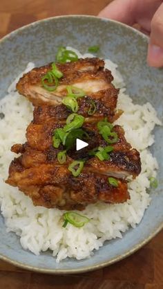 someone is holding a plate with rice and meat on it, which includes green onions