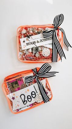 two orange bags filled with candy and candies on top of a white table next to each other