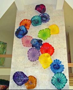 colorful glass flowers are arranged on the wall in this art work, which is part of a staircase