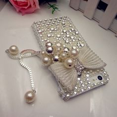 a cell phone case with pearls on it and a rose next to it, sitting on a table