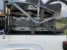 the back end of a white truck with a bike strapped to it's trunk