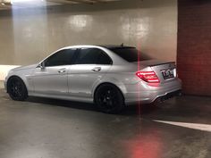 a silver car parked in a parking garage next to a red brick wall and floor