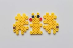 two yellow and black beads are next to each other on a white surface, with one bead in the shape of a giraffe