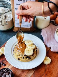 a person is spooning peanut butter over a cookie with banana slices on the side