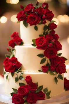 a three tiered white cake with red roses on it