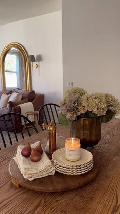 a wooden table topped with a vase filled with flowers next to a candle and other items