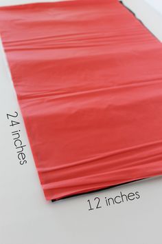 a red sheet that is on top of a white surface with measurements for the width