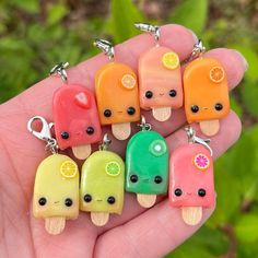 small popsicle charms with fruit and ice cream on them are being held in a person's hand