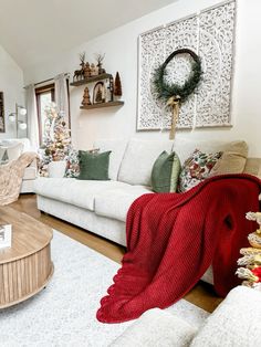 a living room filled with white furniture and christmas wreaths on the wall above it