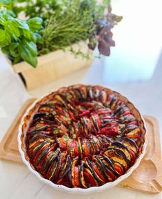 a pie sitting on top of a wooden cutting board next to a potted plant