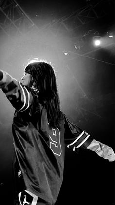 a man with long hair holding a microphone in his hand and pointing to the sky