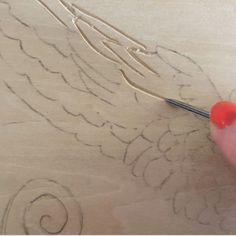 someone is using a pair of scissors to cut out the design on a piece of wood