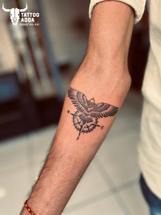 a tattoo on the arm of a man with an eagle and compass in black ink