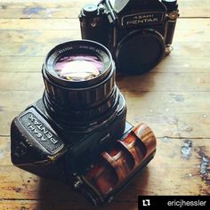 two old cameras sitting next to each other on a wooden table with the lens up