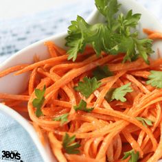 a white bowl filled with carrots and parsley on top of a blue towel