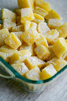 a glass dish filled with cubed pineapples on top of a wooden table