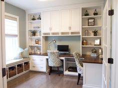 a home office with built - in desk and storage cabinets, along with two chairs