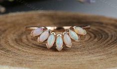 three opalite stone rings sitting on top of a piece of wood with flowers in the background