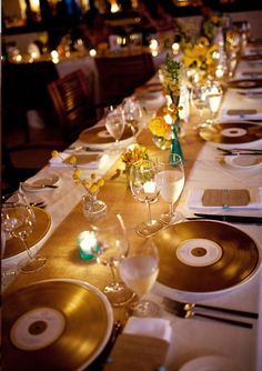 a long table is set with gold plates and place settings for dinner guests to enjoy