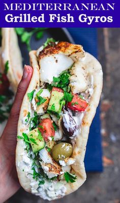 a hand holding a pita filled with vegetables